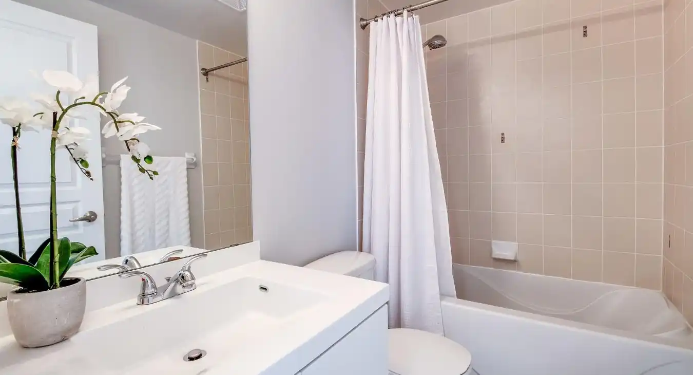 Interior of a modern bathroom with white sanitary ware. Including a compact sink a totilet and a bath with shower. Typical of a bathroom in a condominium